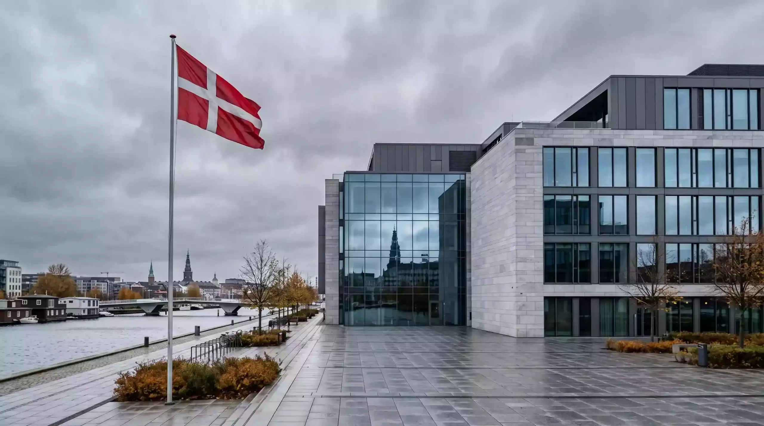 Facade af moderne skandinavisk kontorbygning i København med dansk flag på flagstang